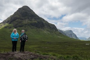 Two women standing beside the mountains of Glencoe