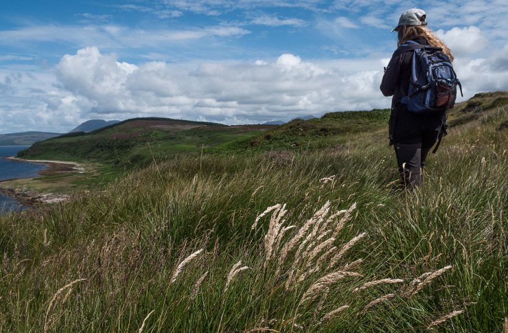 Girl standing in long grass with views across the Arran coastline