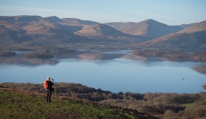 Girl standing near Conic Hill taking photos of Loch Lomond and the mountains