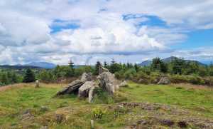 Large slabs of stone on a hill which are the remains of a neolithic tomb