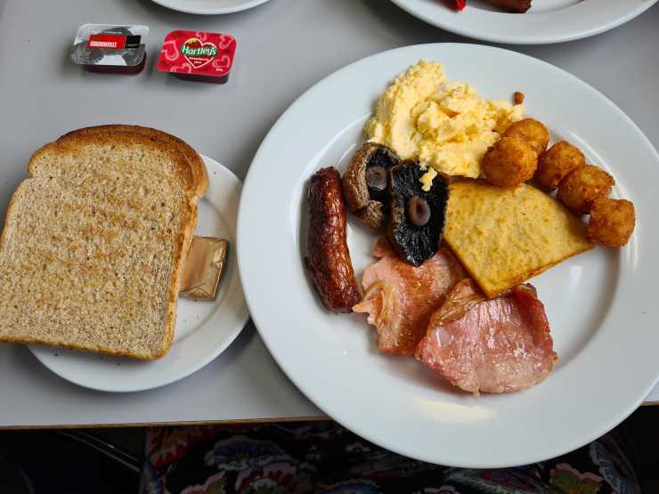 Toast, bacon, sausage link, mushrooms, scrambled egg, has browns and potatoe scone