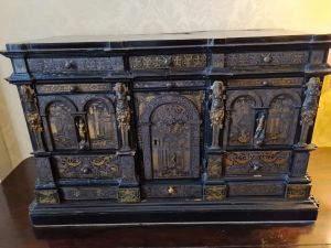 Wooden cabinet with lots of drawers, carvings and a door in the middle