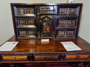 Large wooden cabinet with paintings, drawers and a door in the middle
