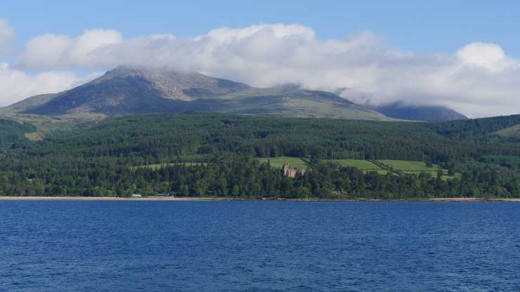 Blue ocean, Brodick Castle in the trees and Goat Fell mountain in the background
