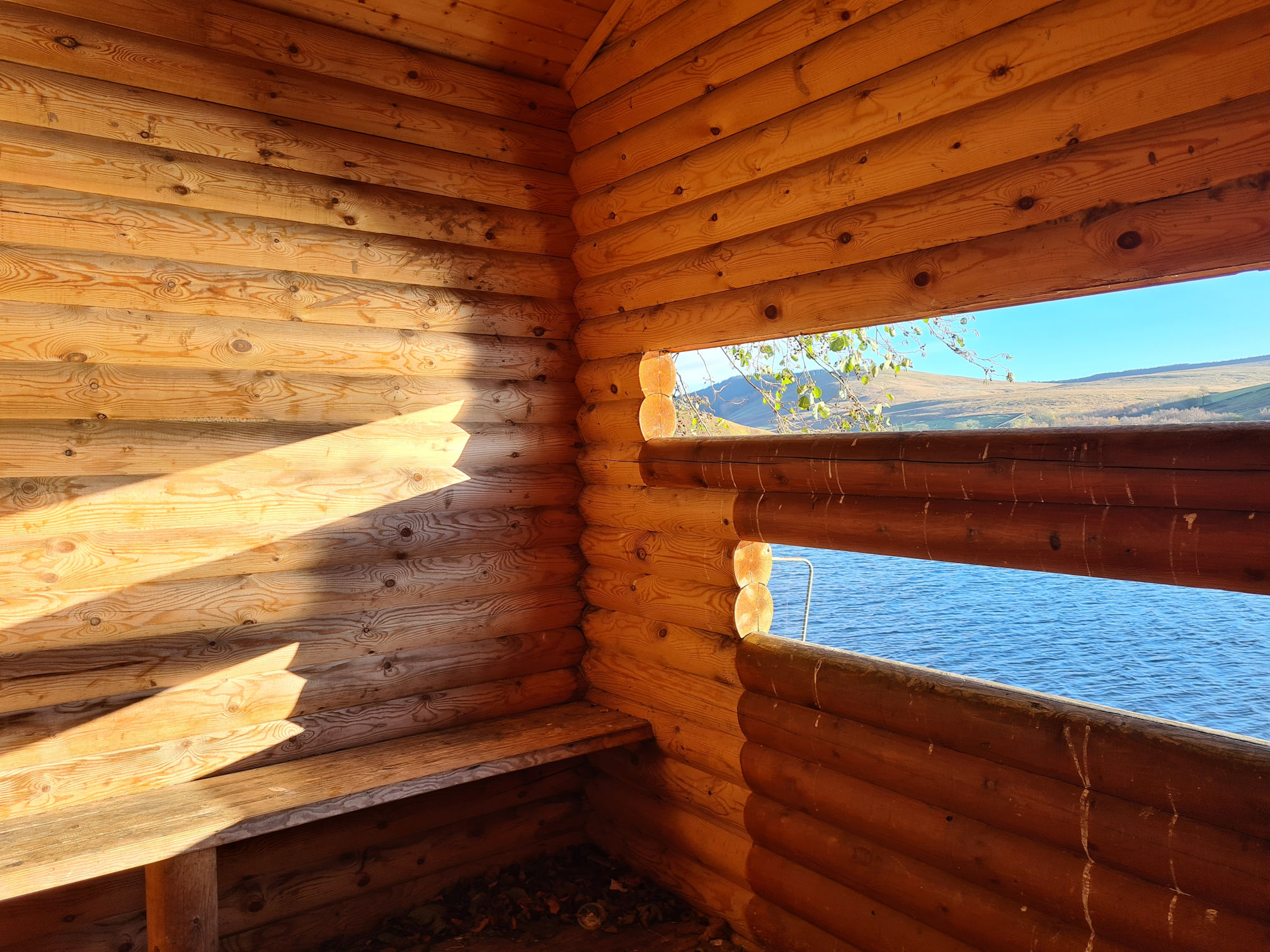Wooden hut with two narrow open window views across a loch