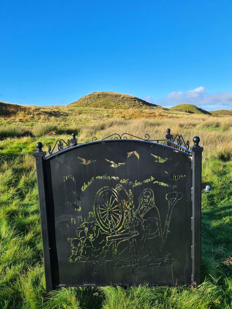 Decorative metal railing with four sides, it has a cut out impression of Tibbie Pagan with her spinning wheel and sheep