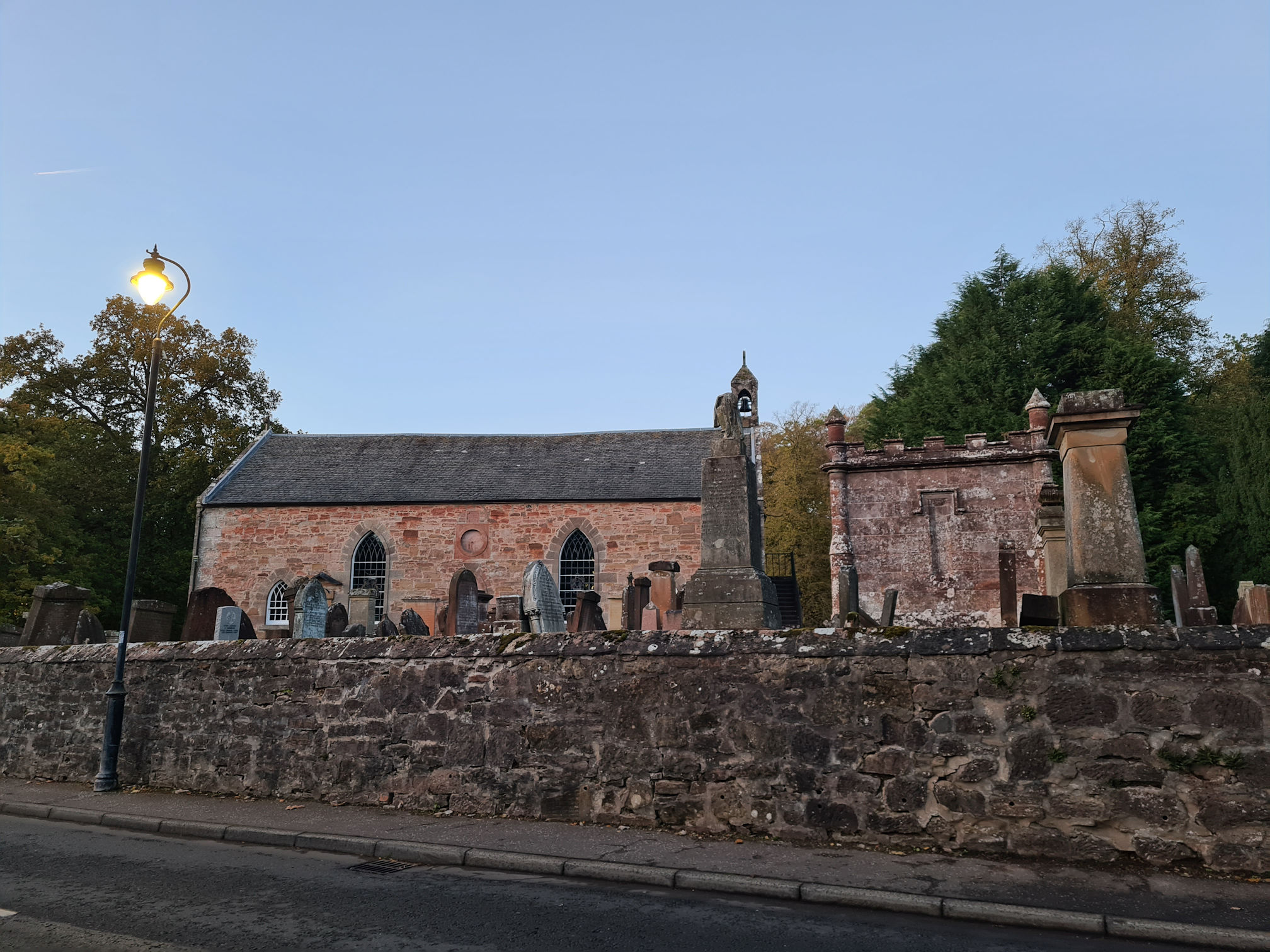 An old church and graveyard, the street light is on