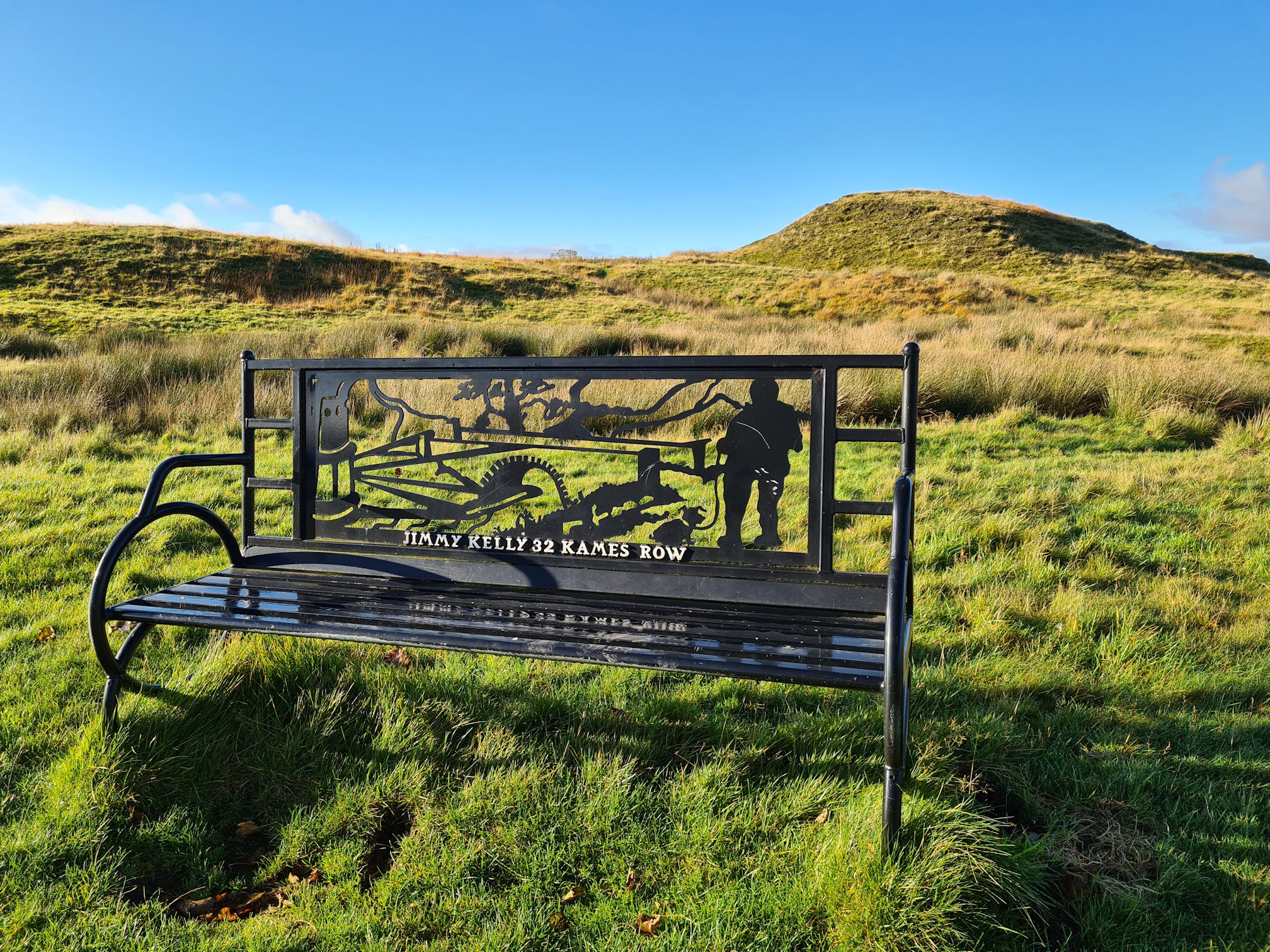 A black metal bench in memory of Jimmy Kelly, 32 Kames Row, Muirkirk