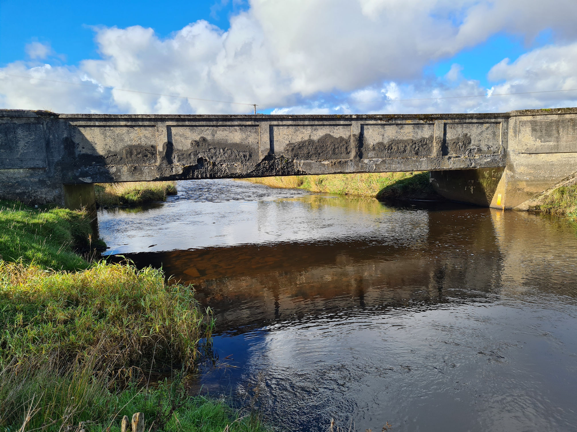 Stone bridge, crumbling with age, the river flows underneath and shining in the sunlight
