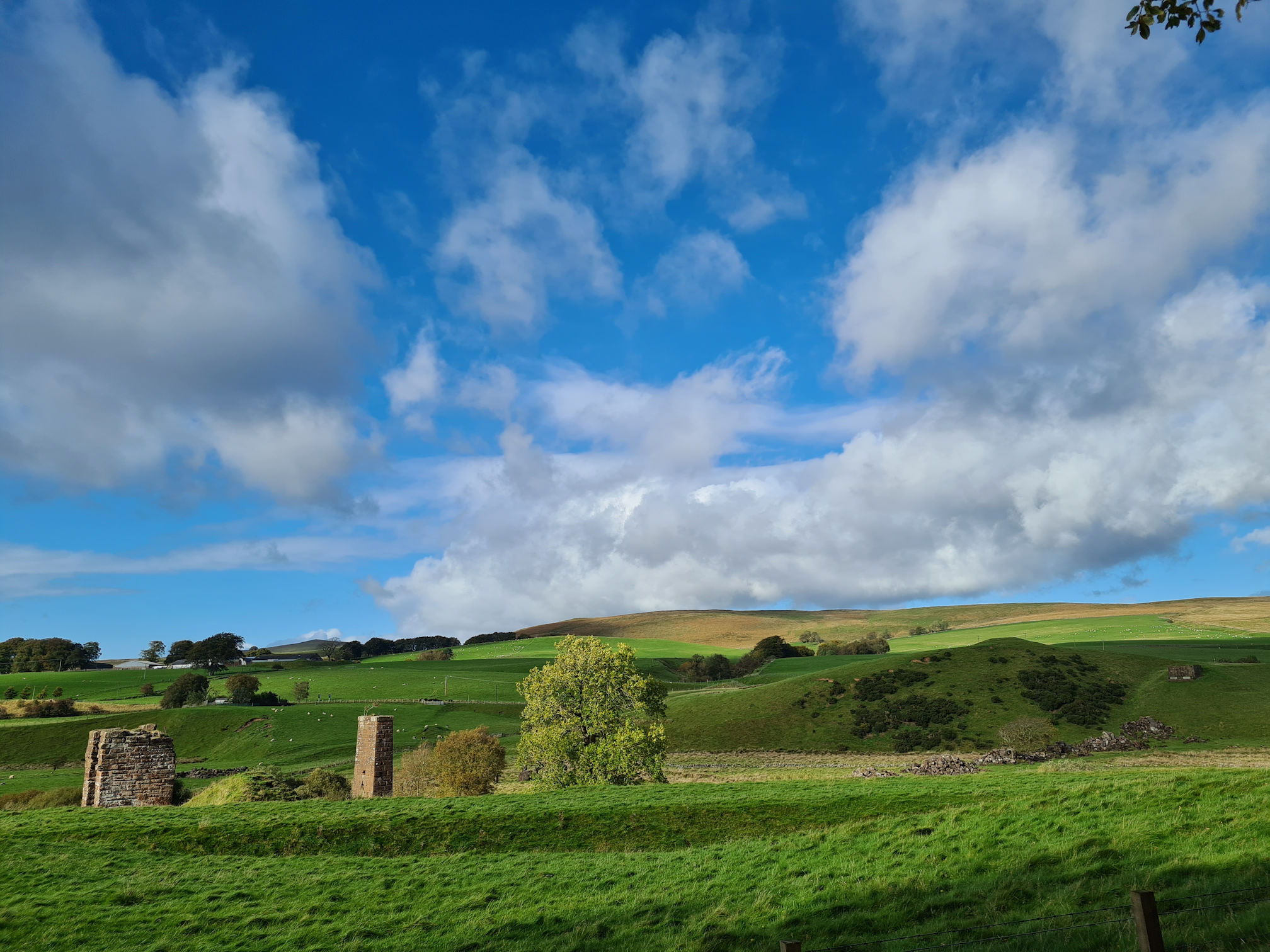Remains of the Auldhouseburn Railway Viaduct, lush green fields, blue sky and white puffy clouds