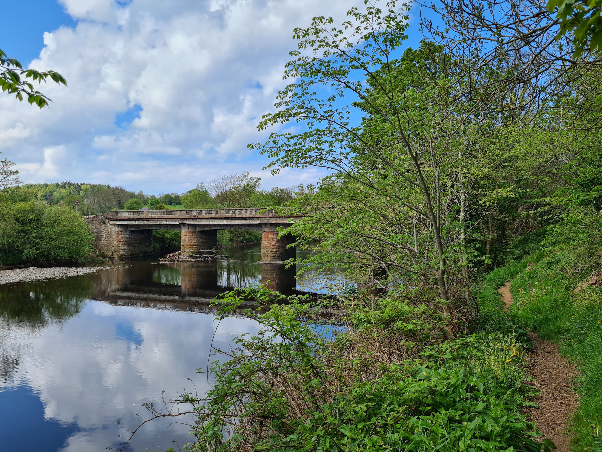 Tarholm Road Bridge over the River Ayr, blue sky and puffy white clouds reflections in the river