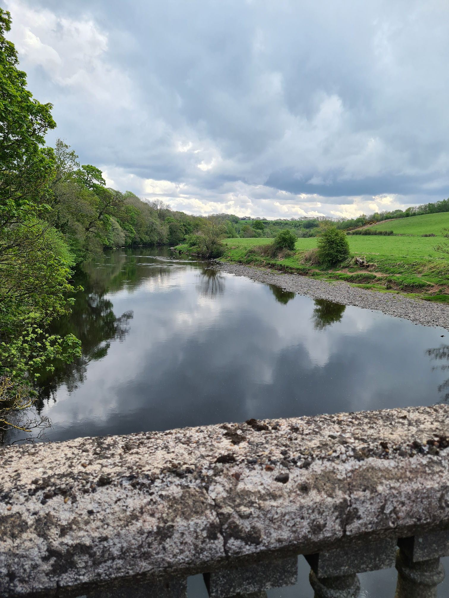 Standing on bridge looking down at a river, it is a cloudy day