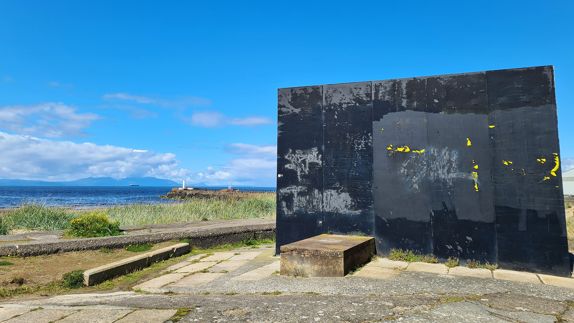 Large monolith shaped sculpture next to a beach - marking the finishing point of the River Ayr Way