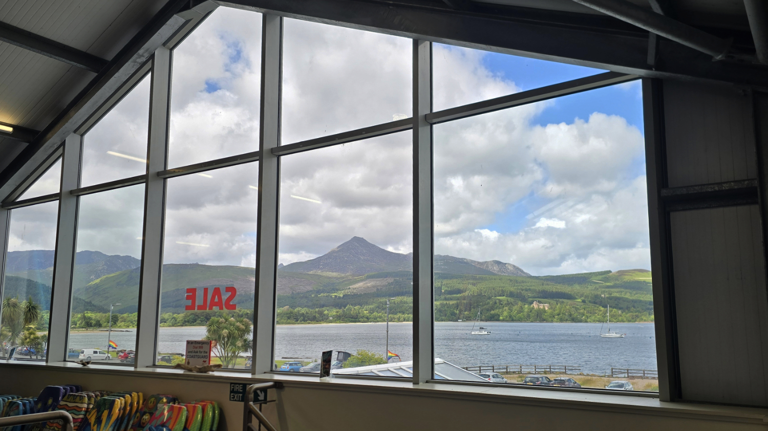 Looking out a tall wide window to a real view of the sea and mountains. The window frames the scene like an advert for getting outdoors.