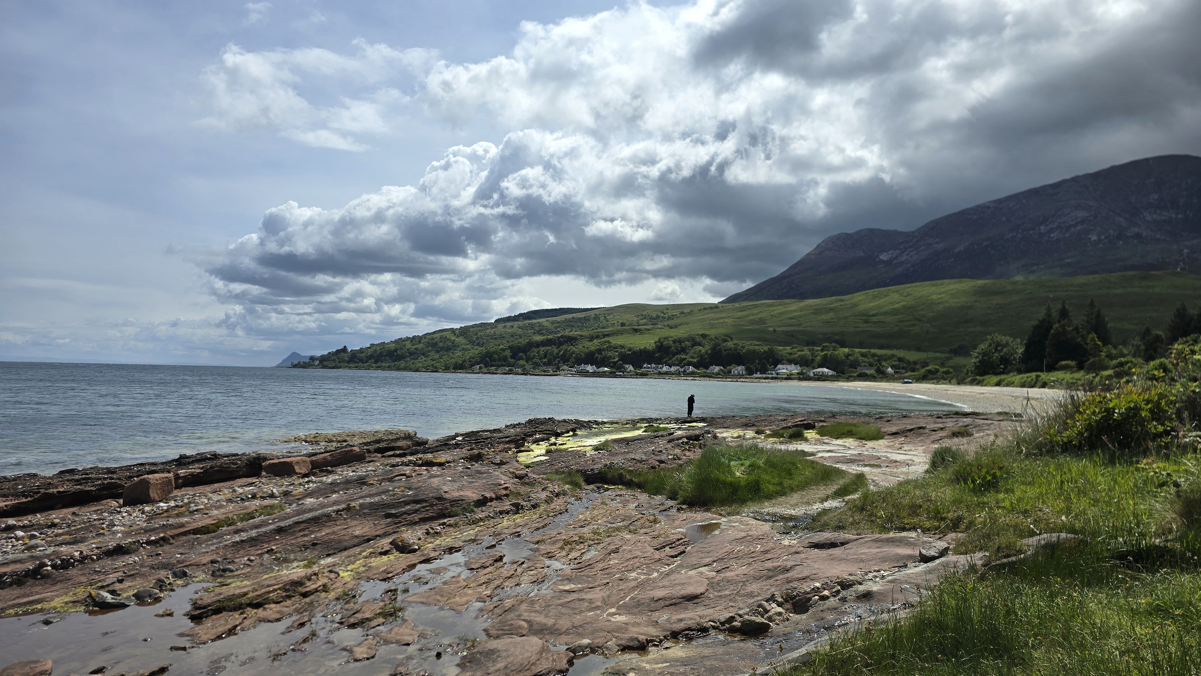 Rocky beach, curved bay, hills, sea and dark clouds coming in