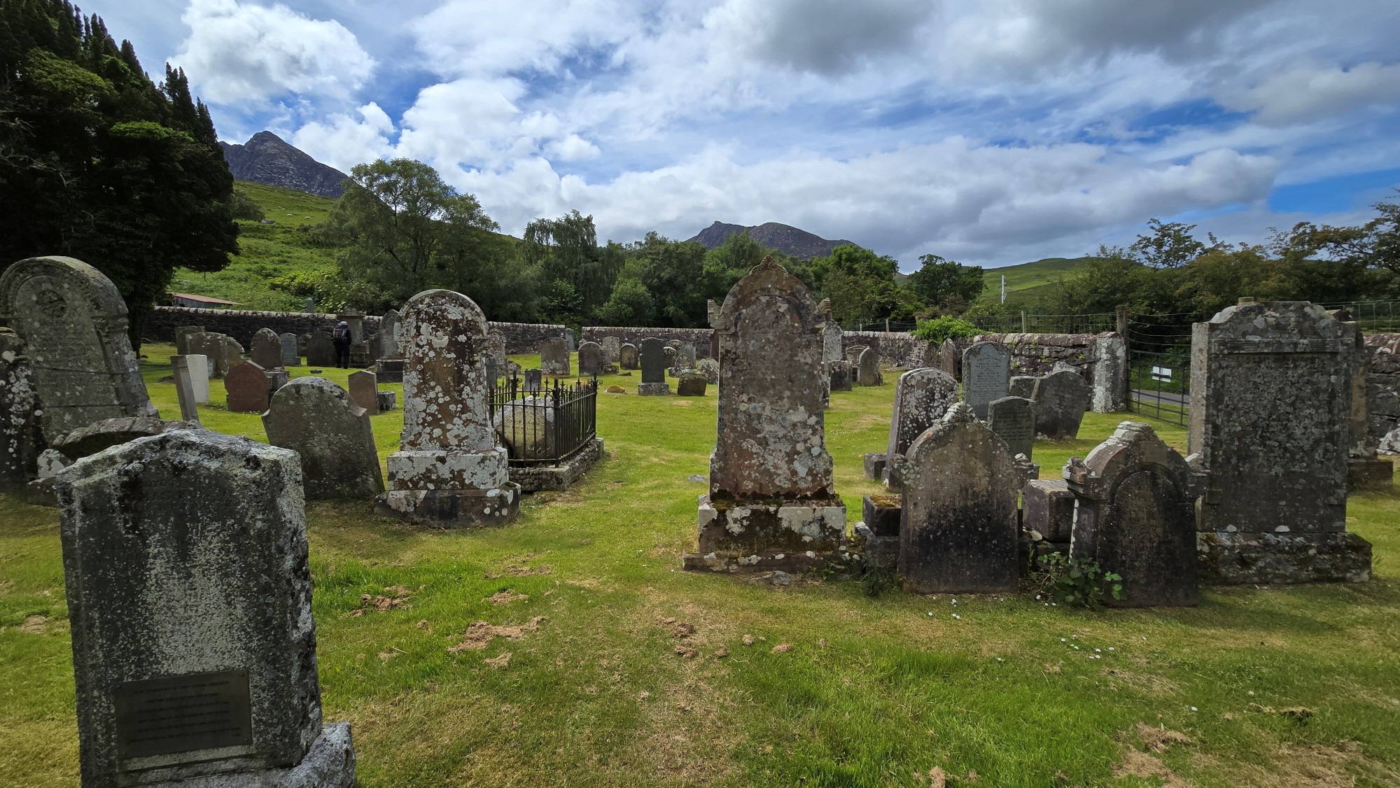 Churchyard burial ground with old headstones and view to mountains of Glen Sannox