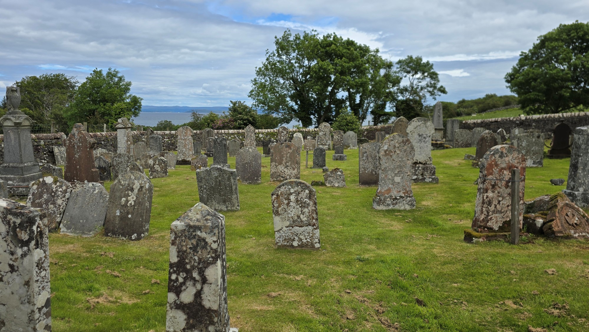 Churchyard burial ground with old headstones and partial view to the sea