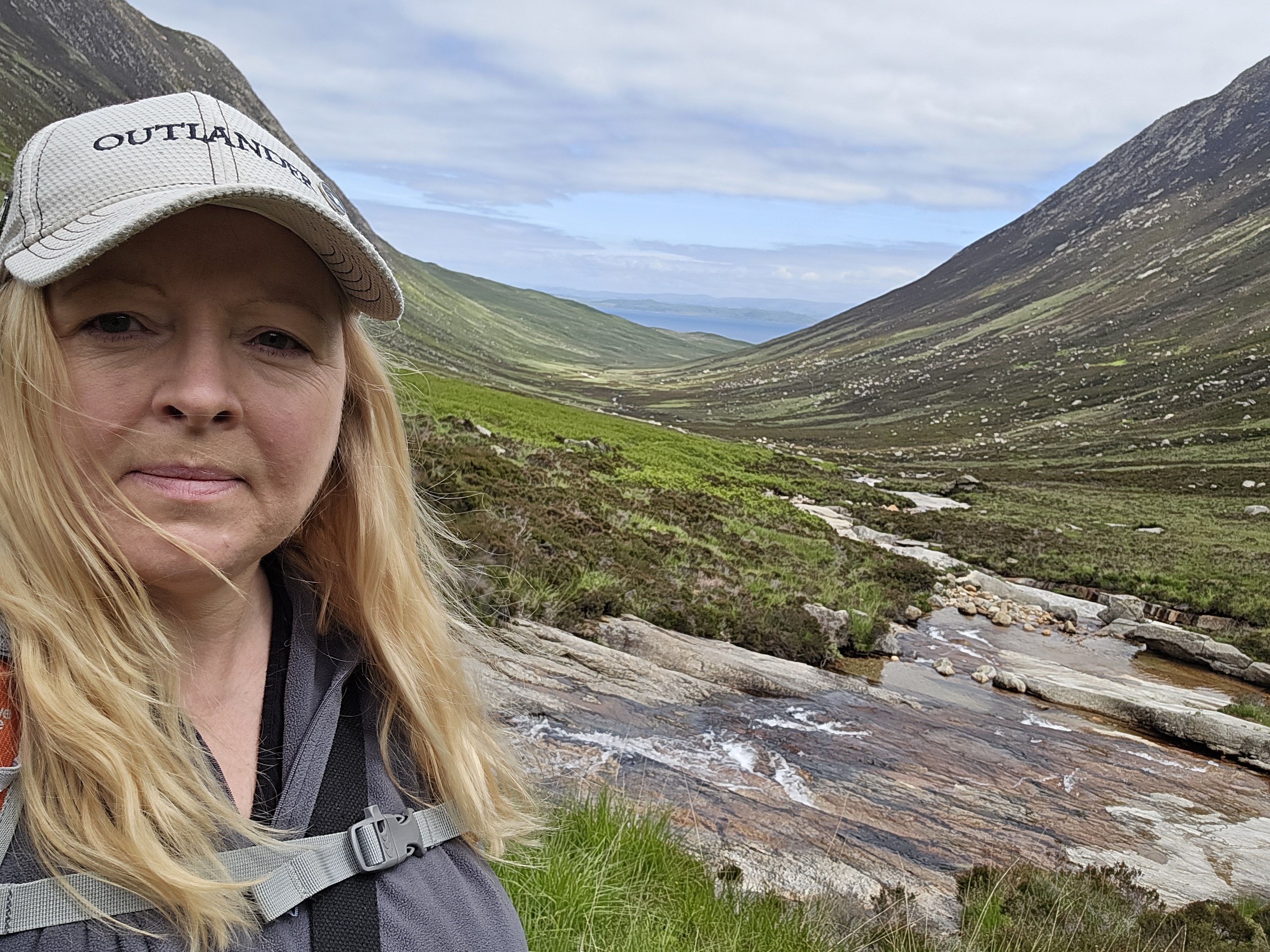 Middle aged woman taking a selfie standing beside the Sannox Burn in Glen Sannox