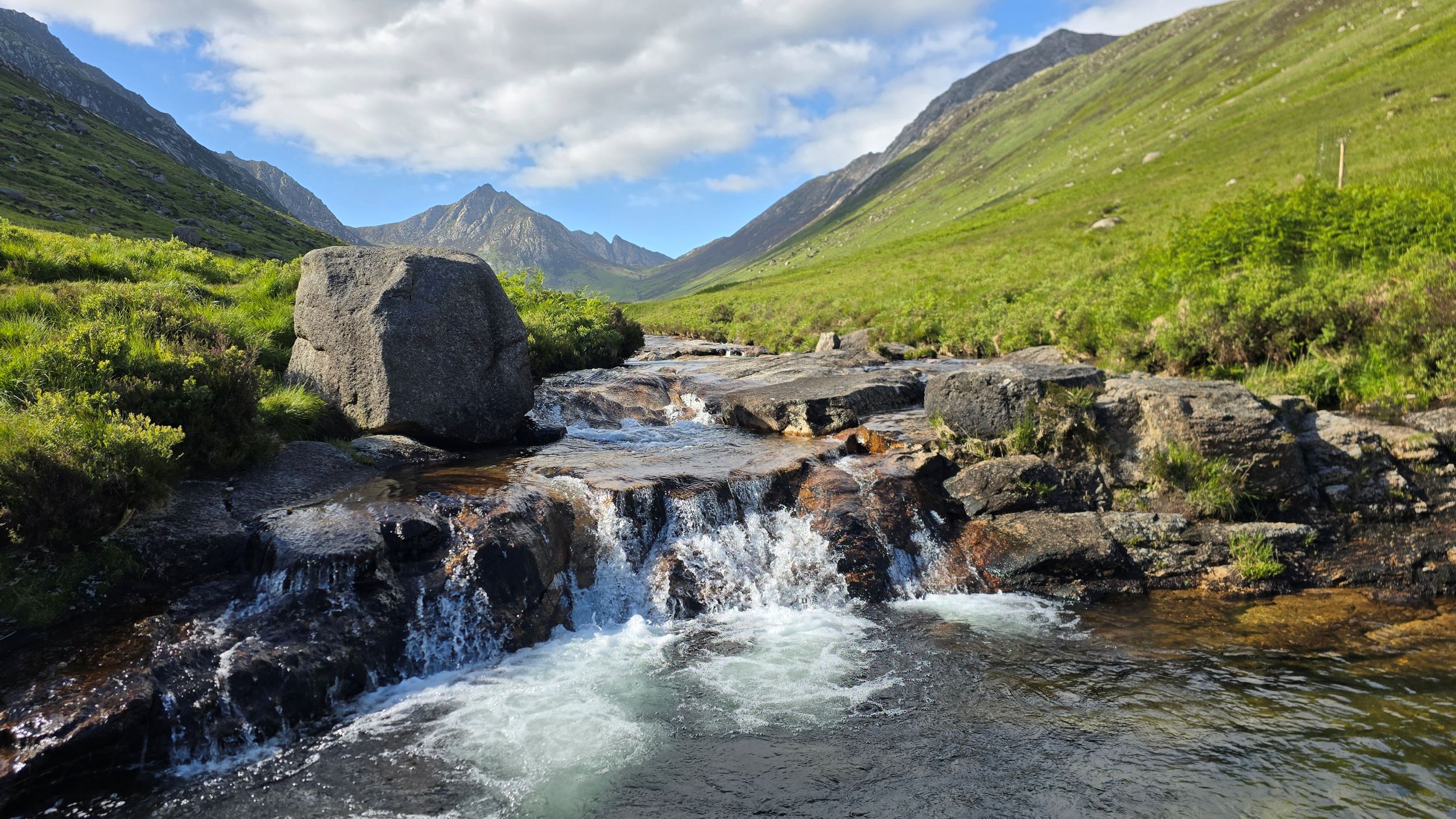 Water falling into a pool with mountains in the distance