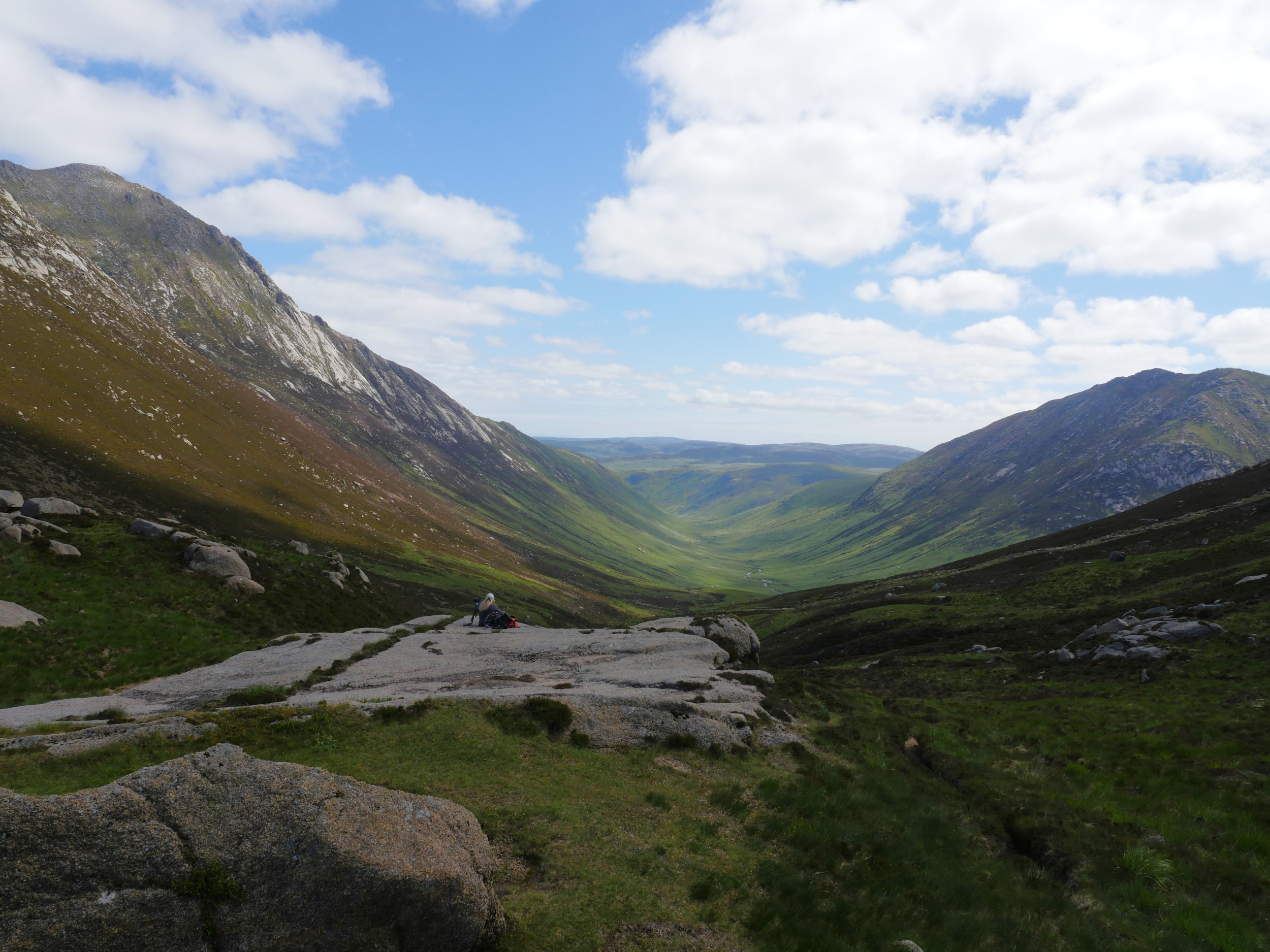 Girl sitting on a rock looking down a picturesque glen