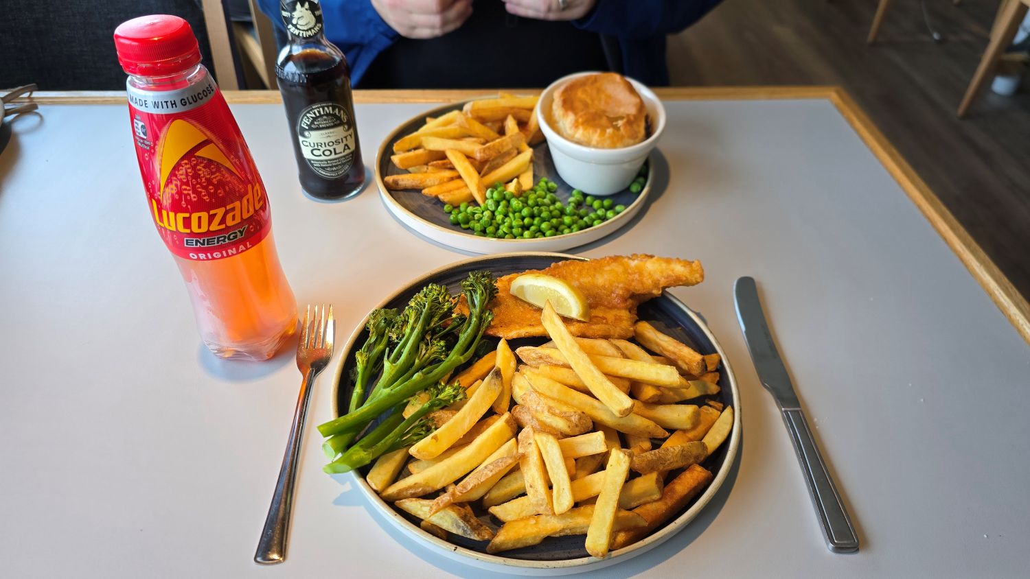 Two meals on a plate, including bottled soft drinks