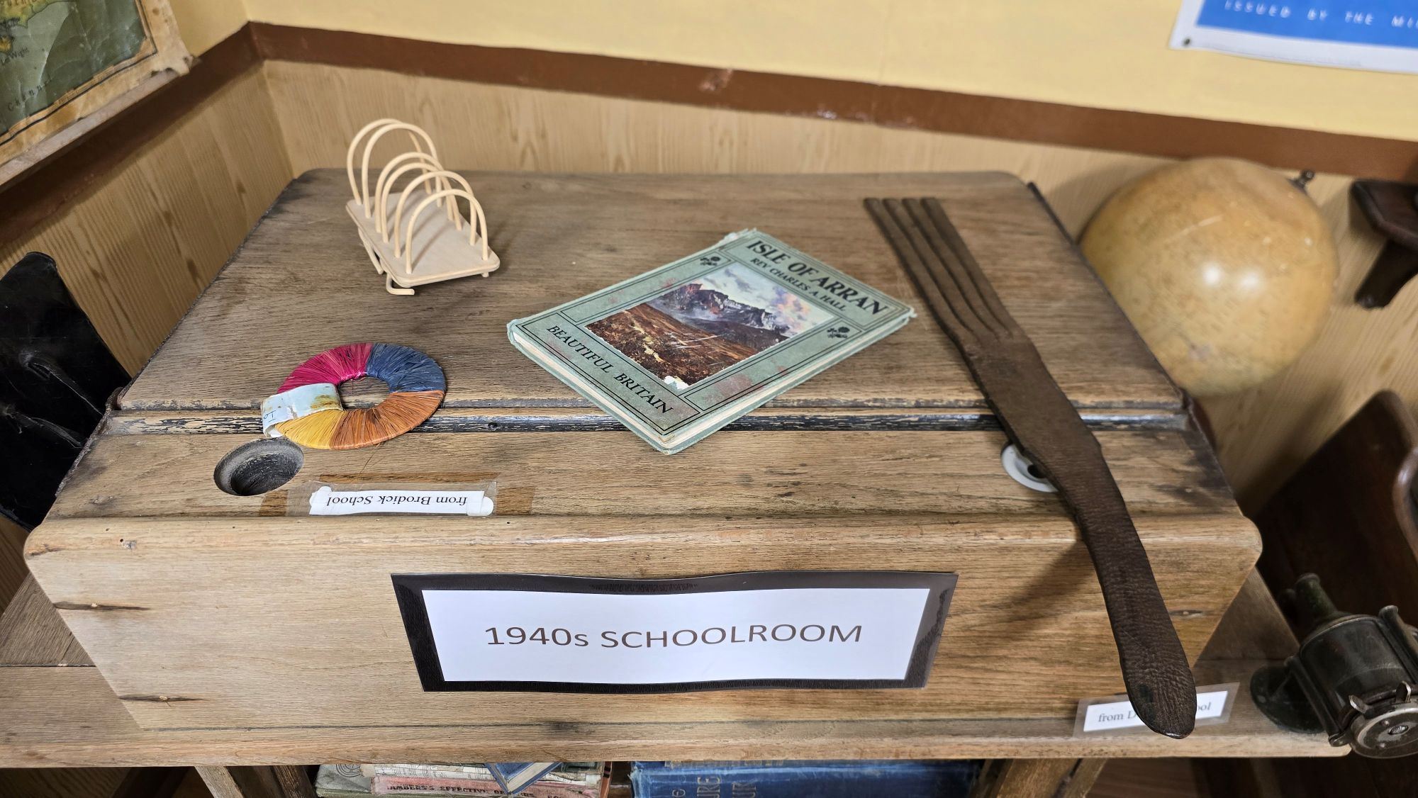 1940s school desk with items on it such as an old leather strap, also known as 'the belt'