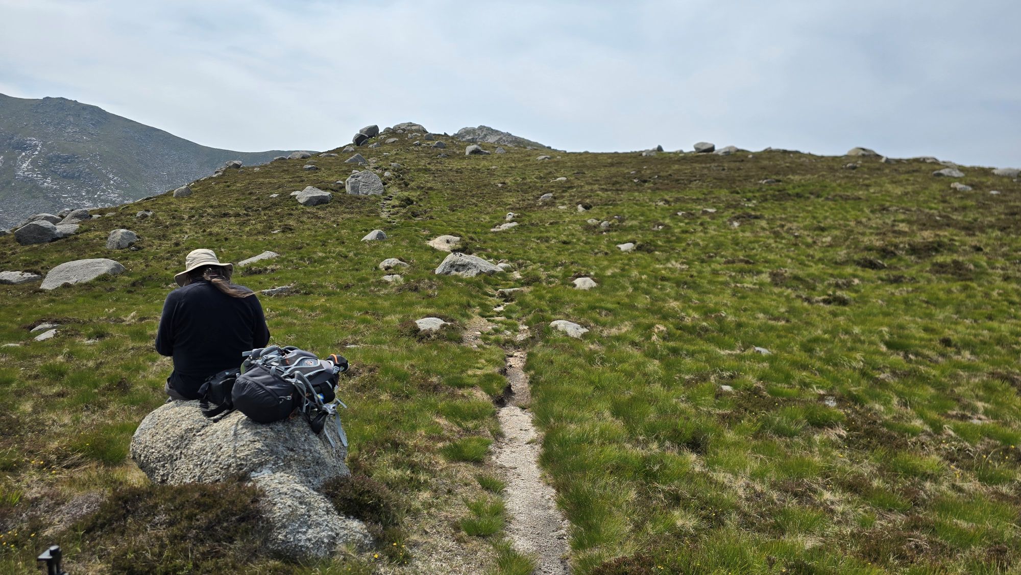 Man sitting on rock on a mountain path