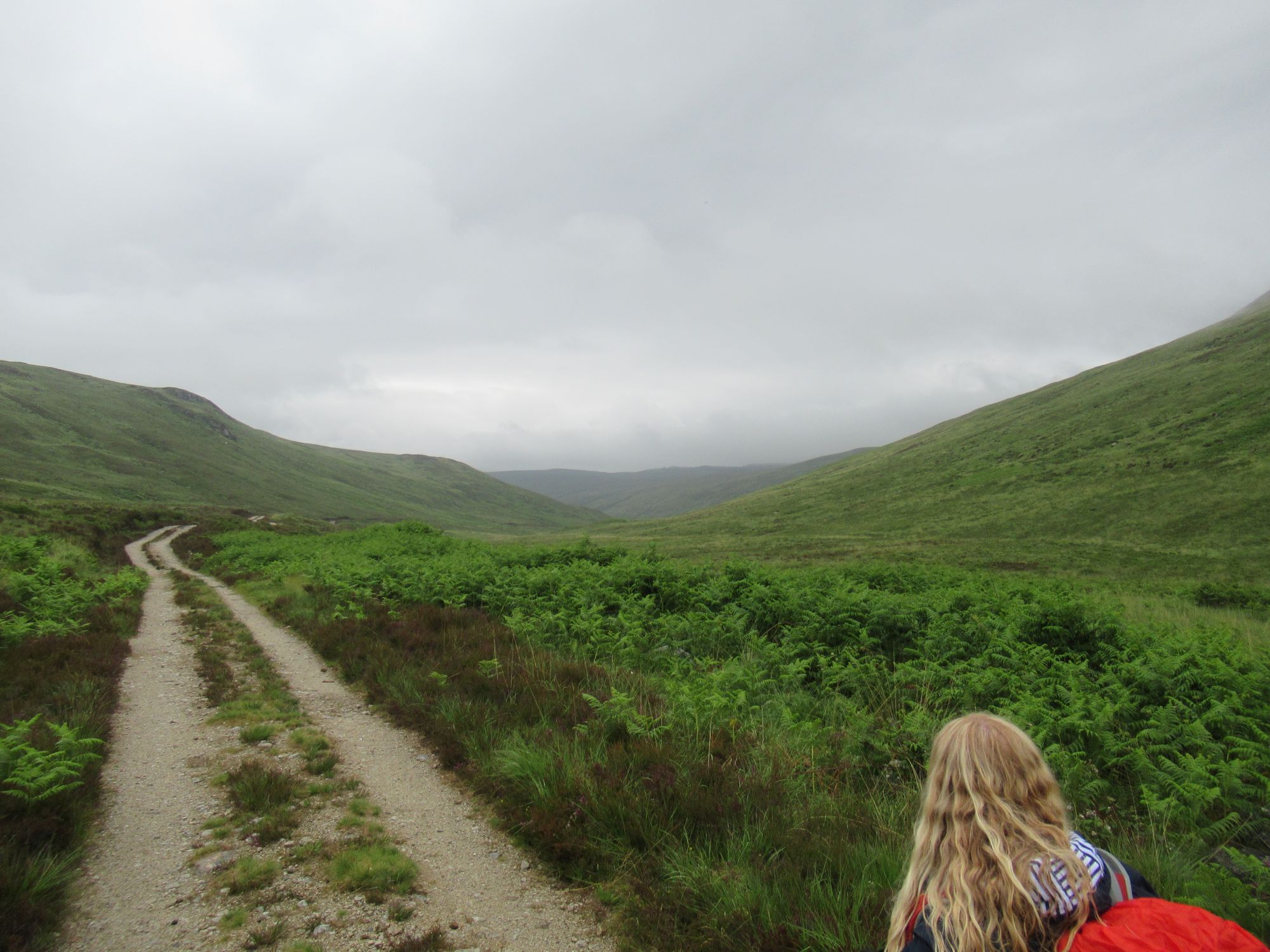 Girl walking along a footpath through a misty glen
