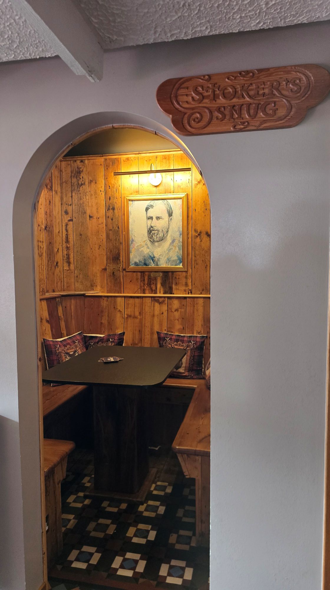 Arched entrance to the Stoker's Snug with one square table and a fitted bench around it to sit and eat and drink