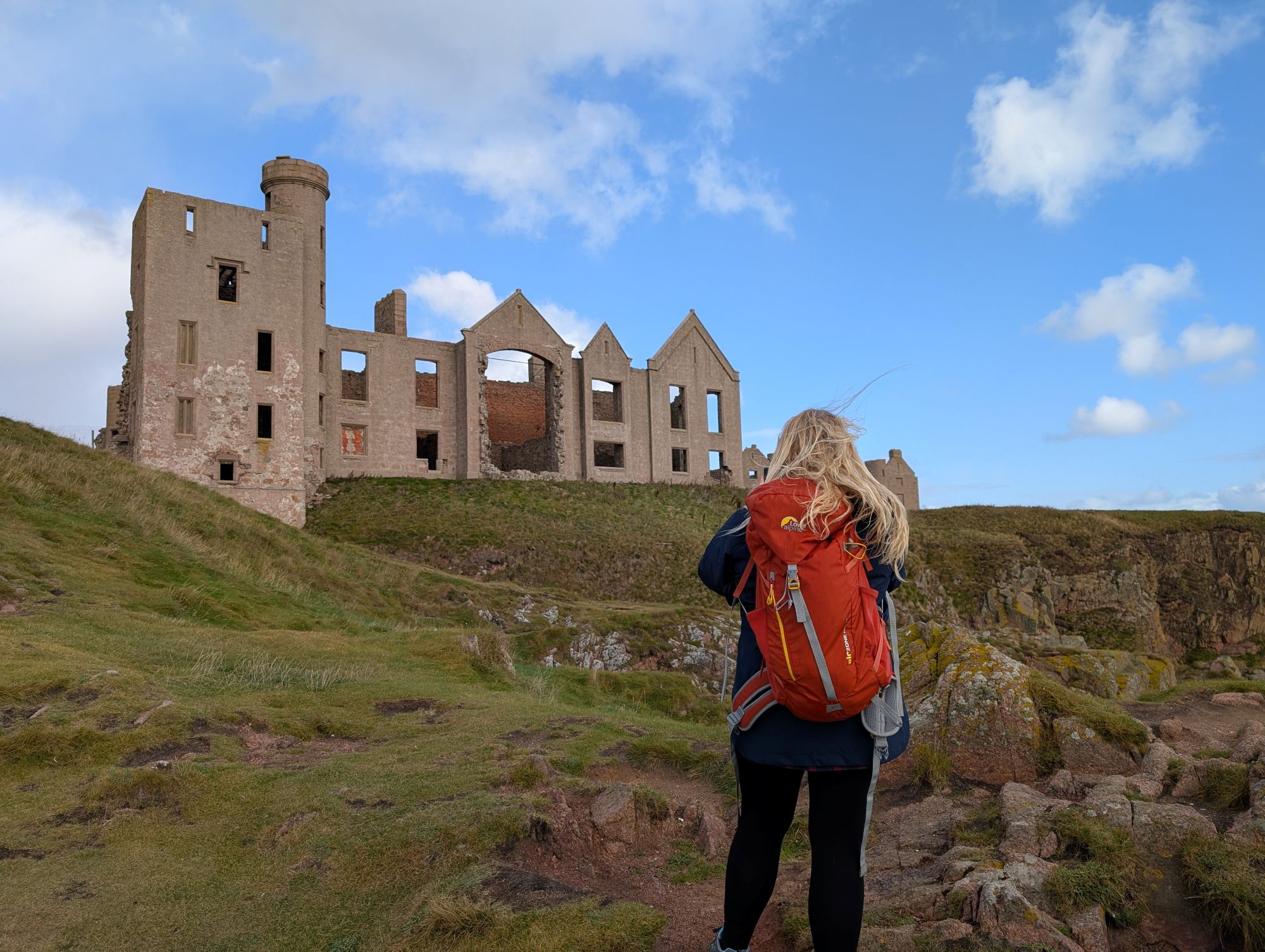 Girl standing taking photos of castle ruins on a clifftop