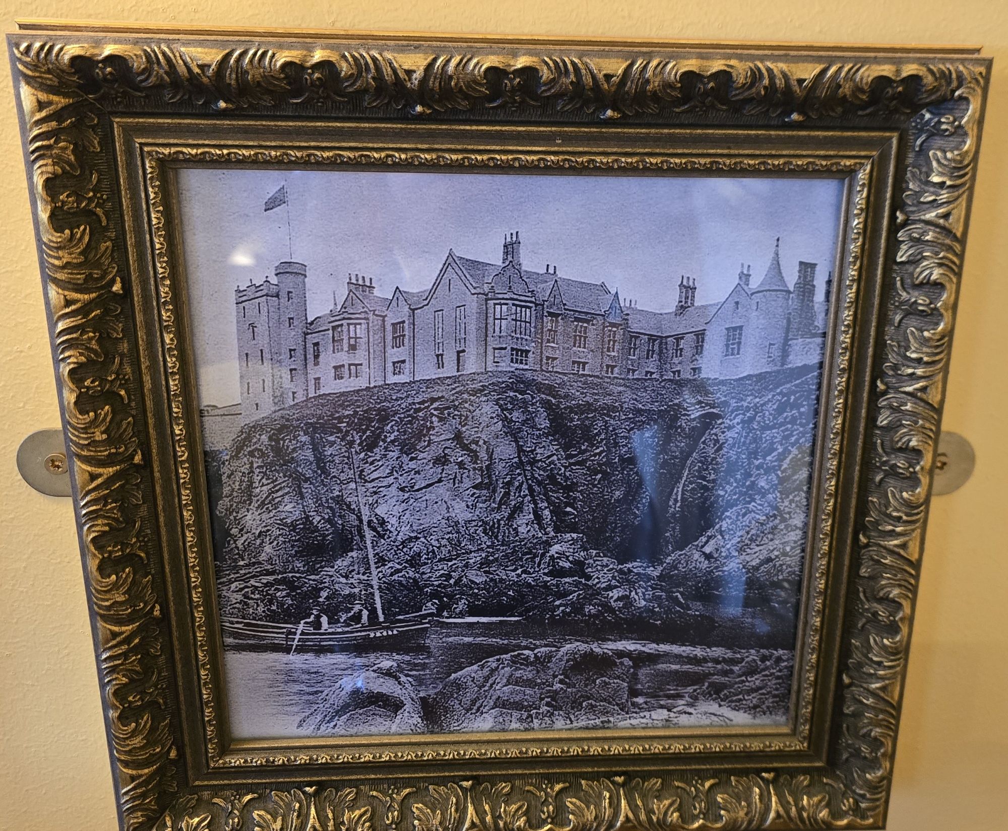 A framed picture showing an old photo of Slains Castle