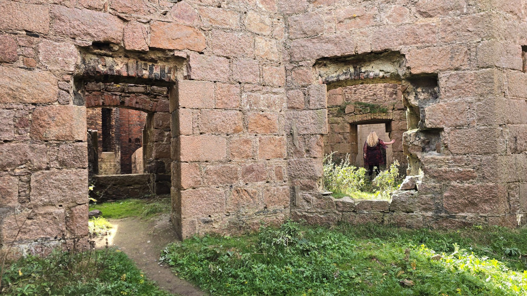 A girl wearing a red dress standing in castle ruins