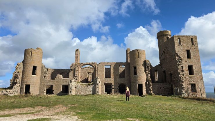 Girl in a red dress standing in front of castle ruins