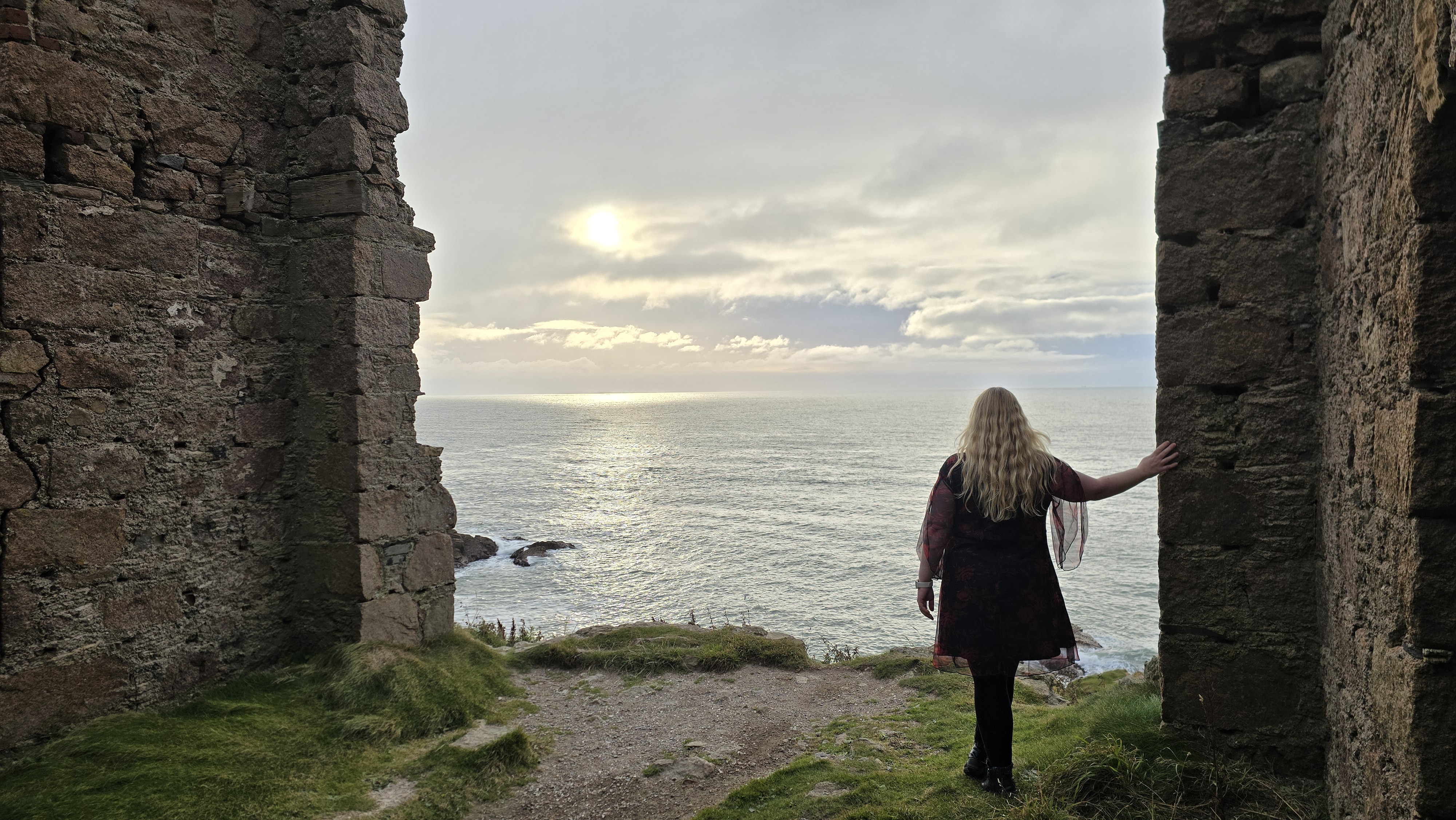 Girl standing inside castle ruins looking out to sea